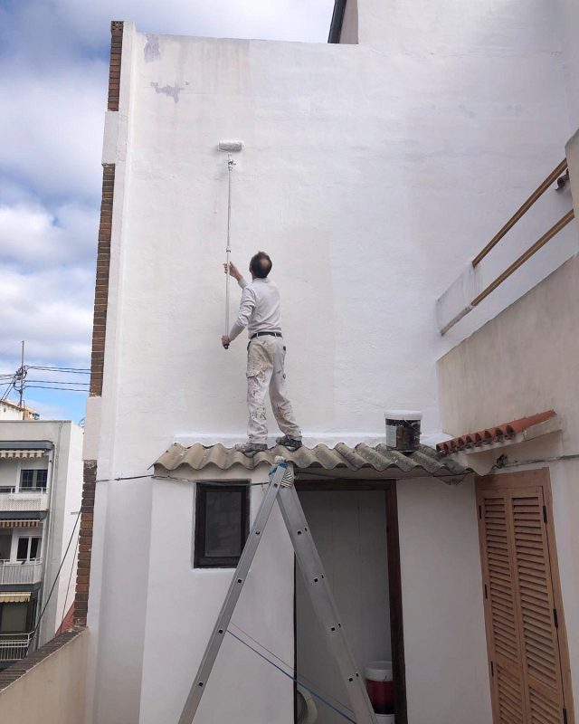 Pintor pintando una fachada con rodillo