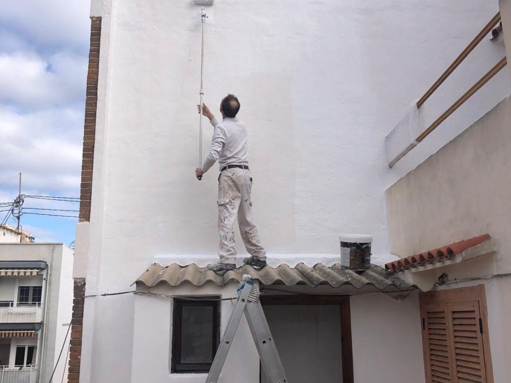 Pintor pintando una fachada con rodillo